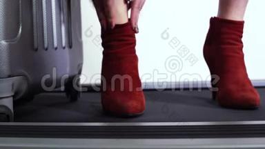 自信的女人，带着手提<strong>箱</strong>，纠正她<strong>时尚</strong>的红色靴子，穿着高跟鞋，站在跑道上。 关门